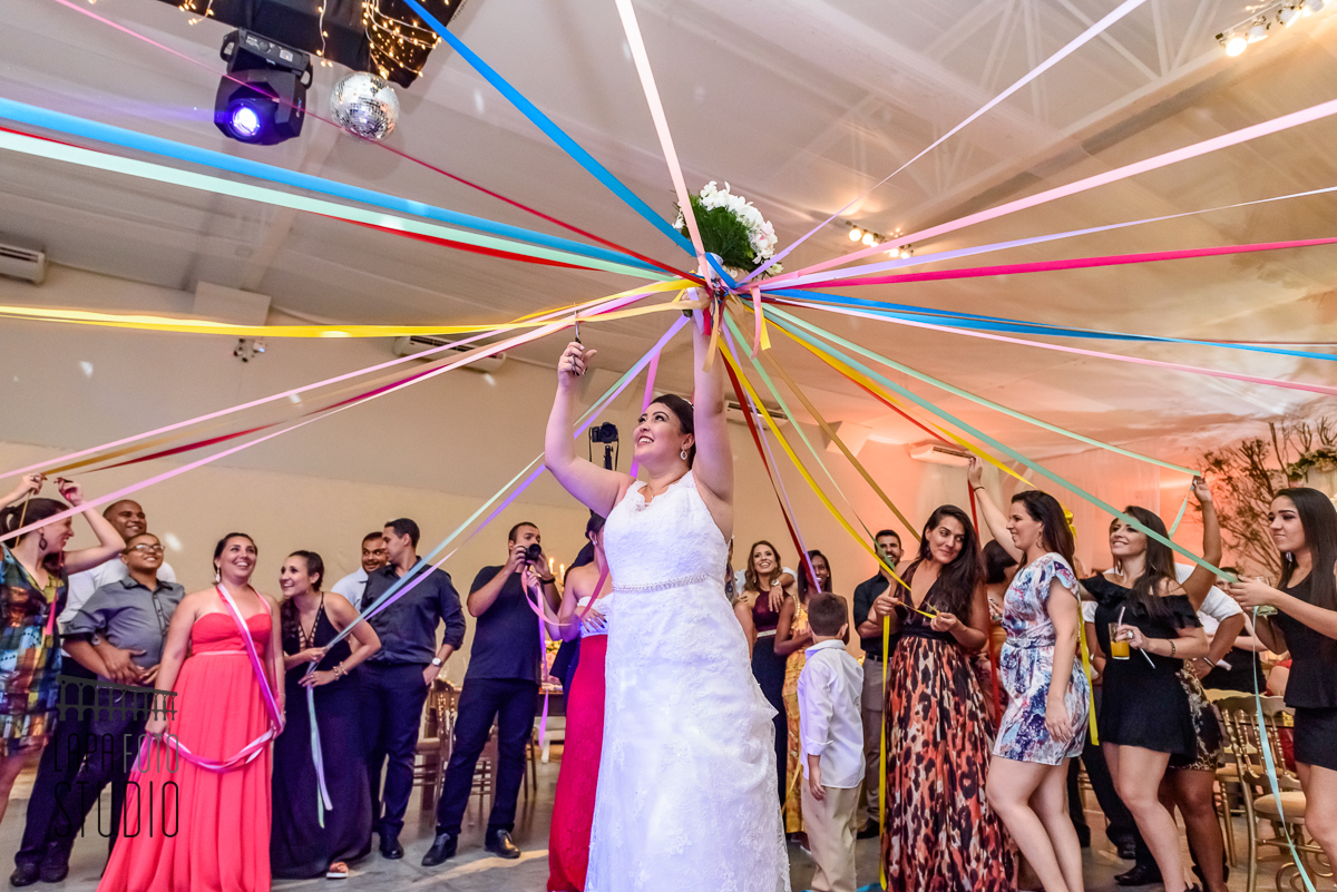 Noiva corta as fitas do buquê na pista de dança durante festa de casamento