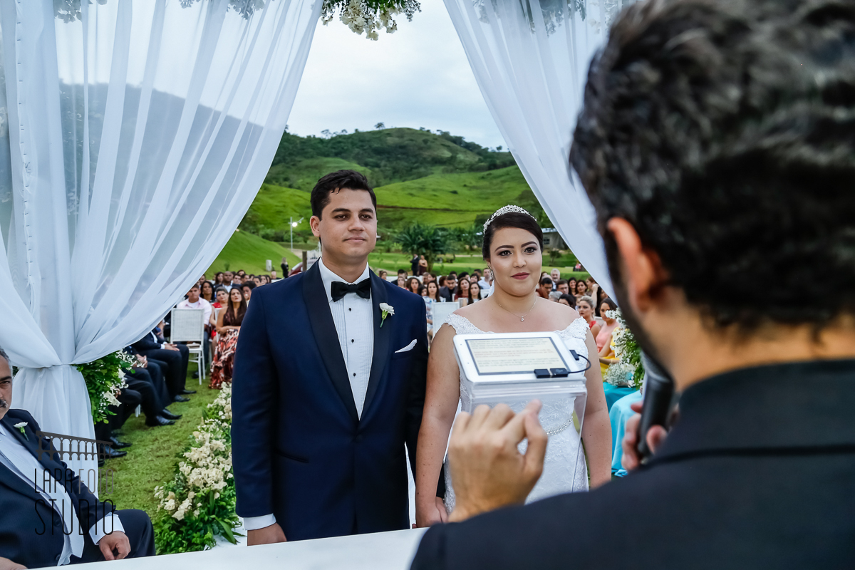 Olhar atento dos noivos para o celebrante durante cerimônia de casamento