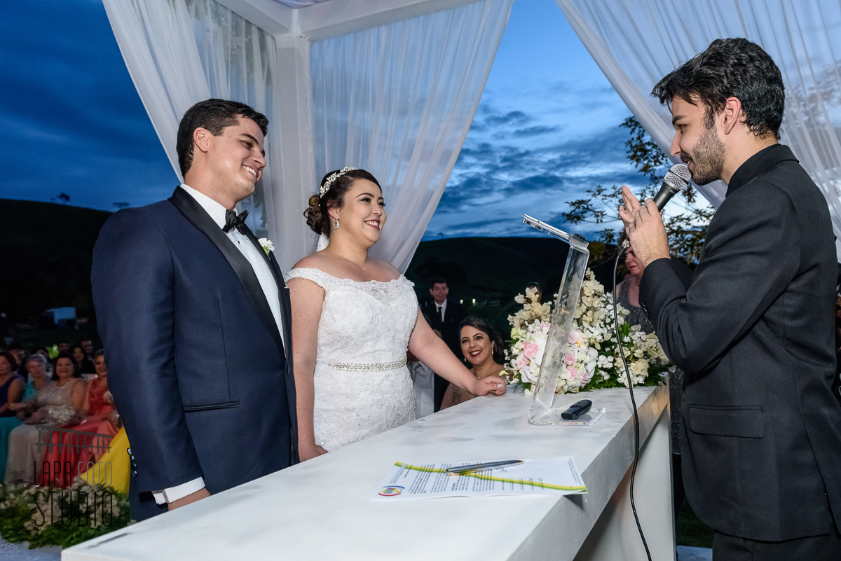 Noivos sorriem para o celebrante durante cerimônia de casamento em Juiz de Fora