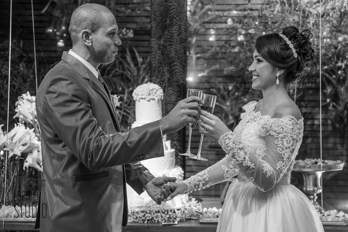 Foto em preto e branco do brinde dos noivos no espaço jardins do vale dos sonhos