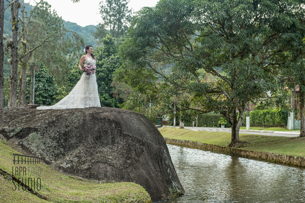 Noiva pronta para casar fotografando em cima de uma pedra com rio abaixo