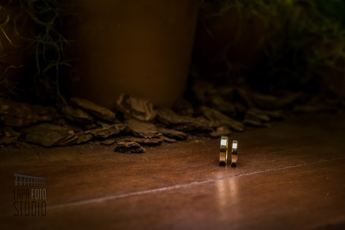 Alianças em cima de uma mesa de madeira com iluminação especial em Mangaratiba