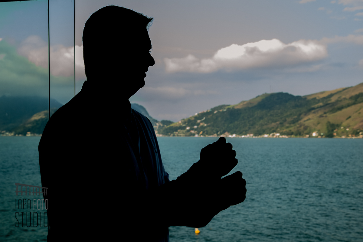 Noivo em contraluz no making of com mar ao fundo