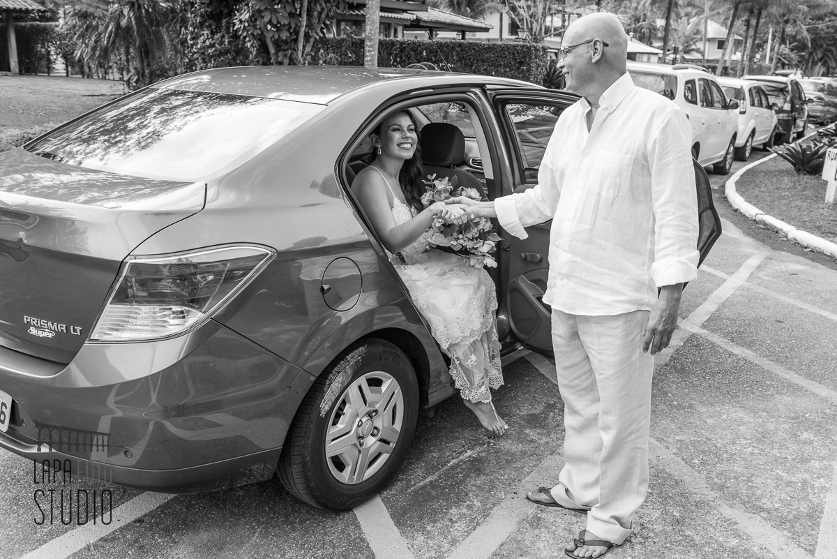 Foto em preto e branco do pai tirando a noiva do carro em mangaratiba