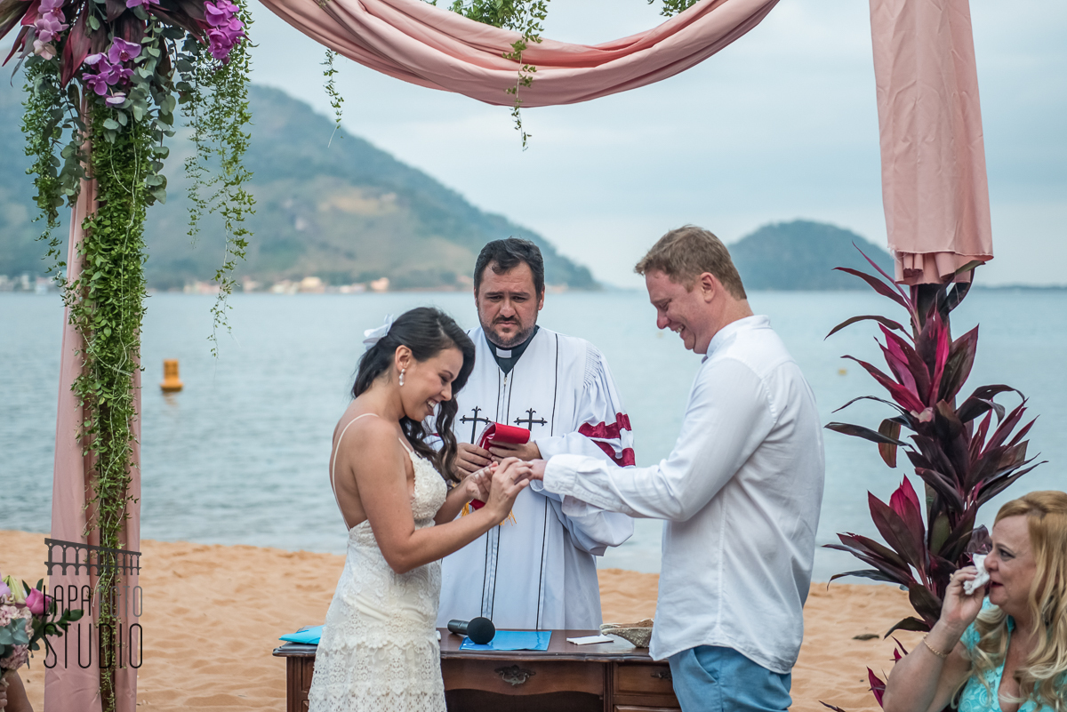 Noiva coloca aliança no noivo durante celebração de casamento na praia