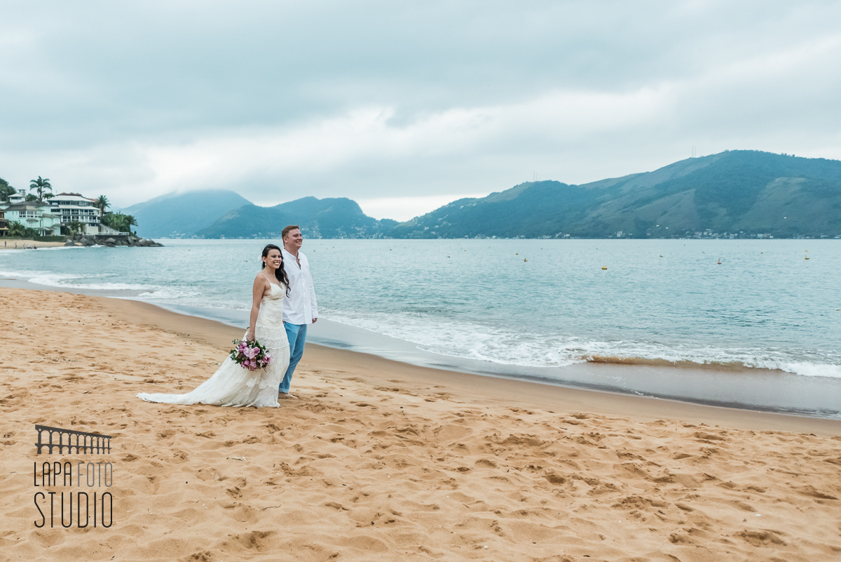 Noivos caminhando na areia no ensaio pós cerimônia em Mangaratiba