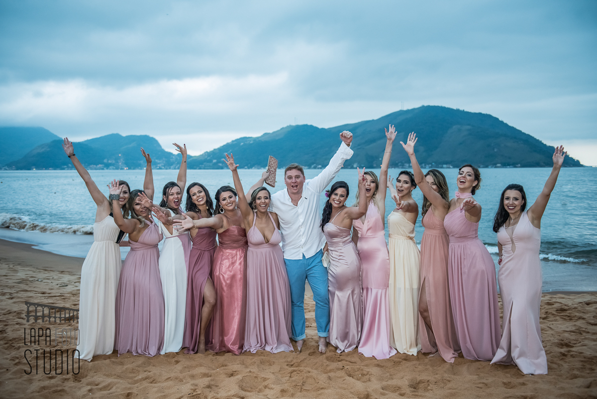 Noivo comemorando com as madrinhas na praia de Mangaratiba durante fotos posadas