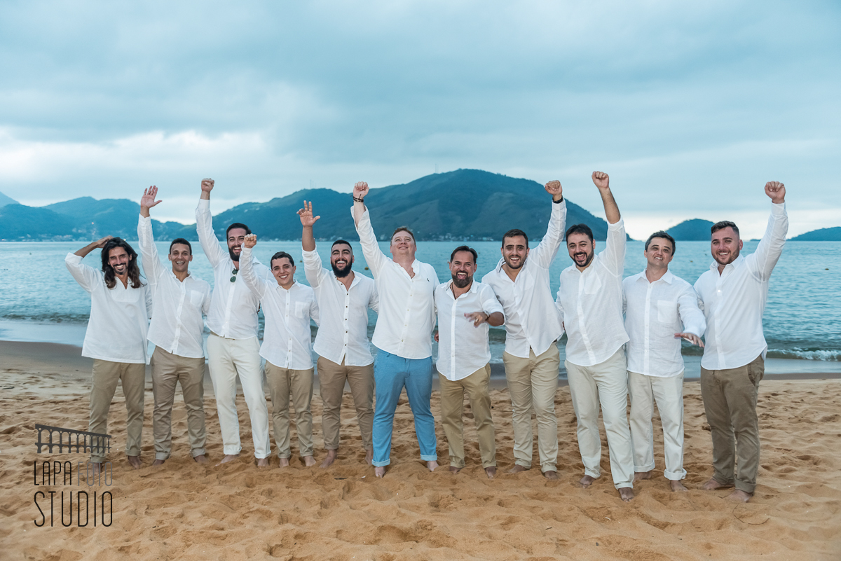 Noivo comemorando com os padrinhos na areia da praia de Mangaratiba durante fotos posadas