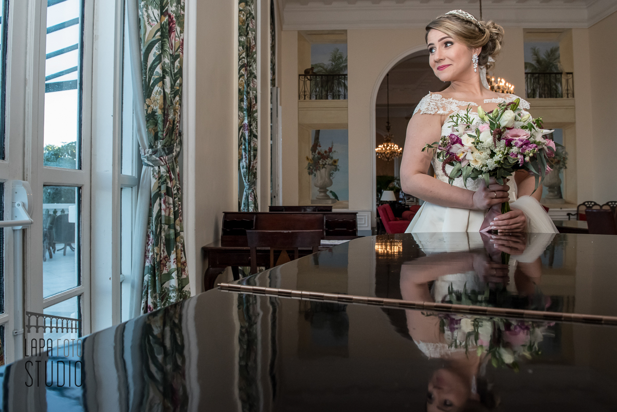 Noiva de lado com luz de janela próxima ao piano do copacabana palace