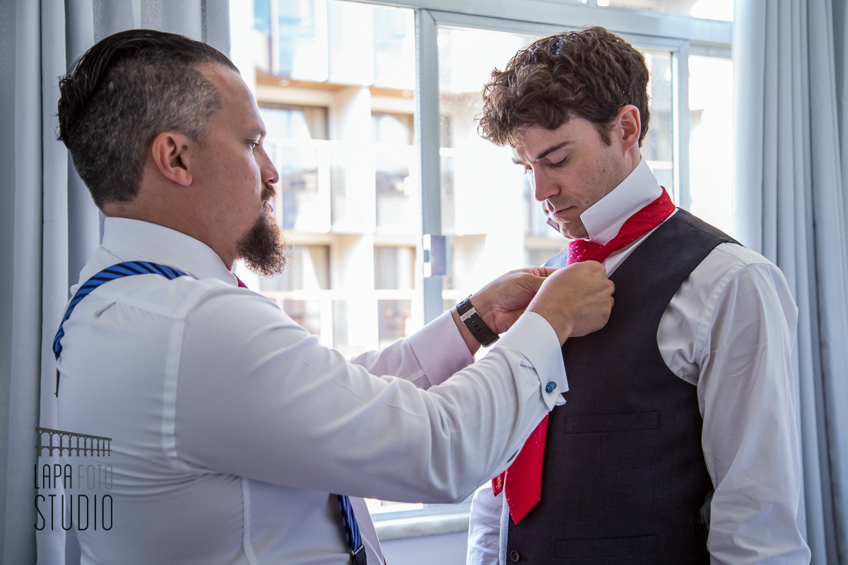 Padrinho ajuda o noivo a fechar a gravata no making of