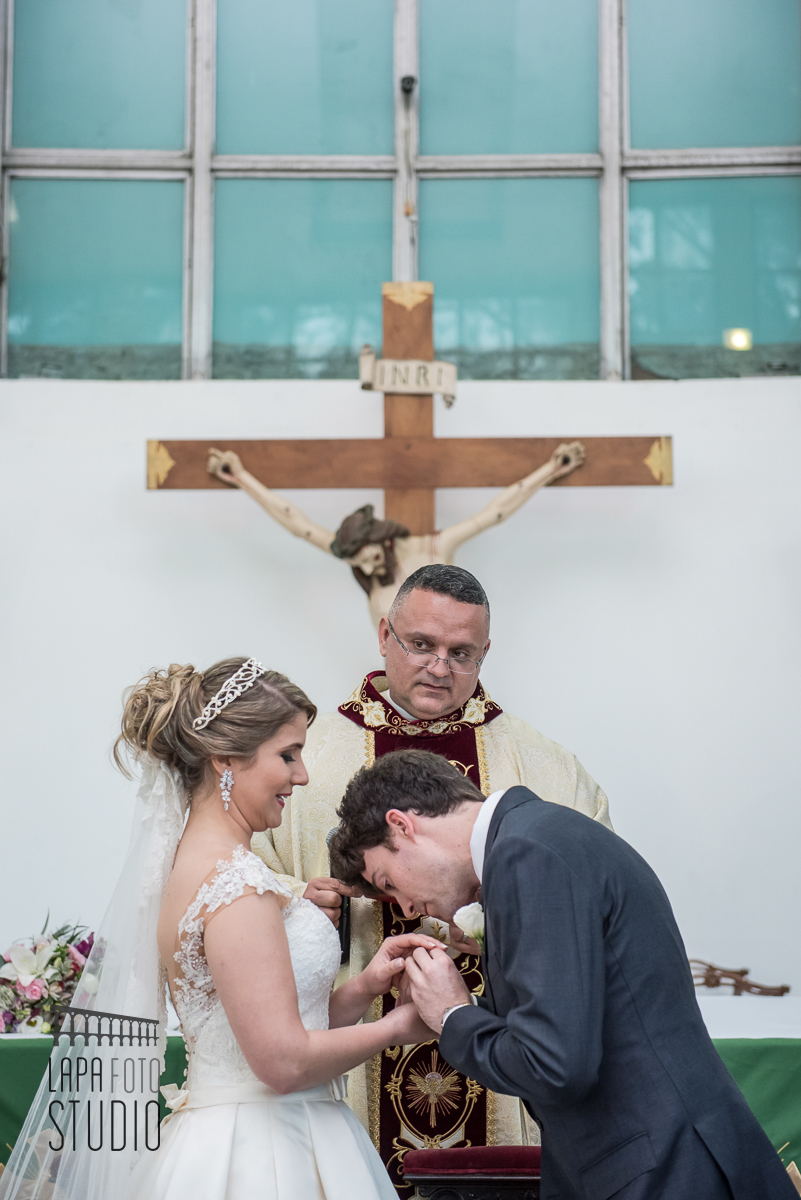 Noivo beija a mãe da noiva durante a troca de alianças no casamento