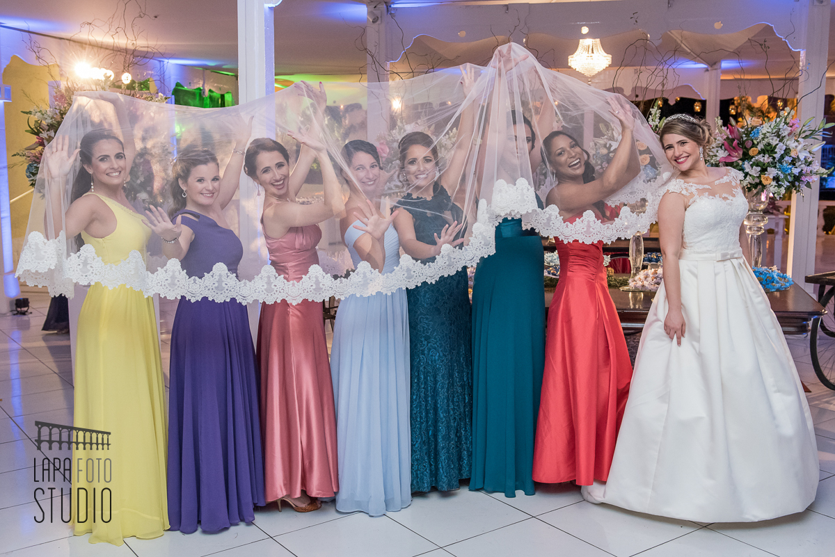 Madrinhas escondidas embaixo do véu da noiva numa foto divertida no dia do casamento