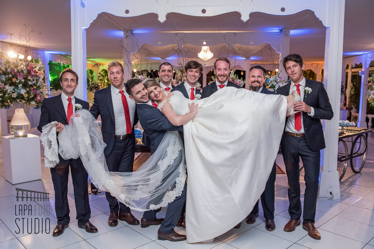 Padrinhos carregam a noiva no colo no ensaio de fotos posadas após cerimônia de casamento