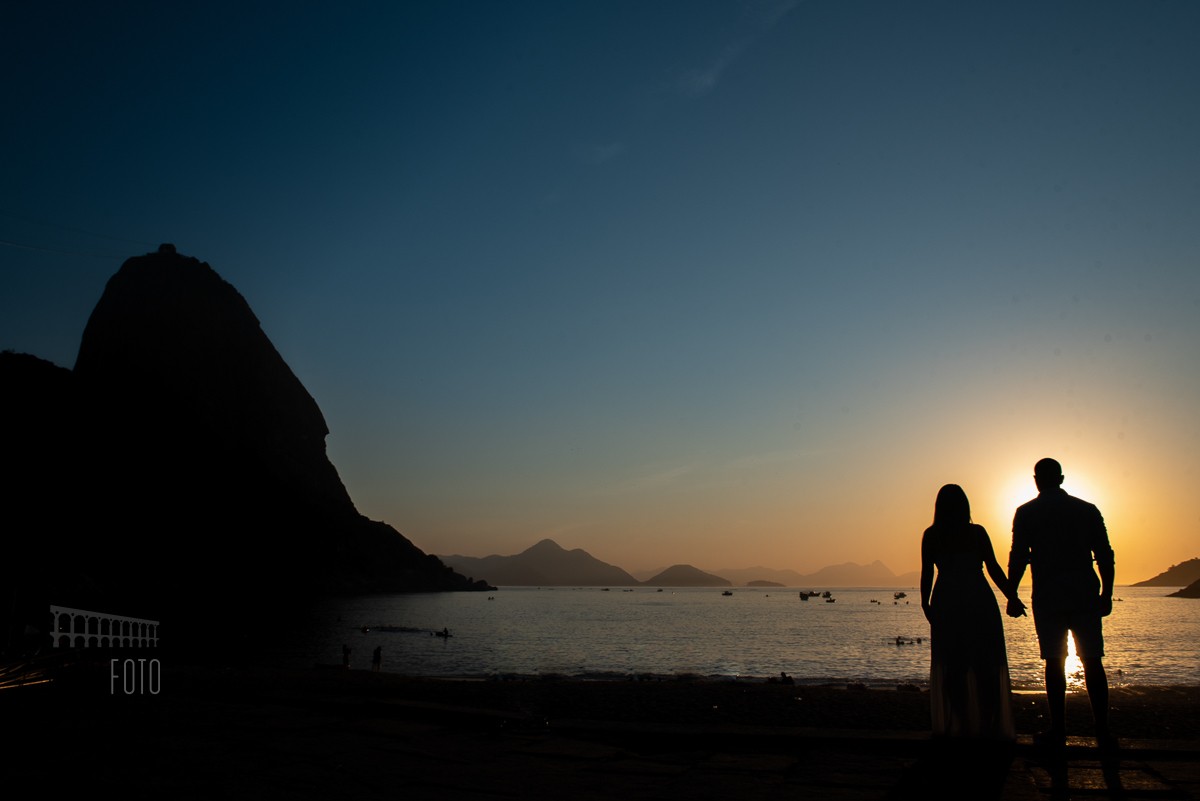 Panorâmica do sol nascendo na praia vermelha com pão de açúcar e noivos em contraluz