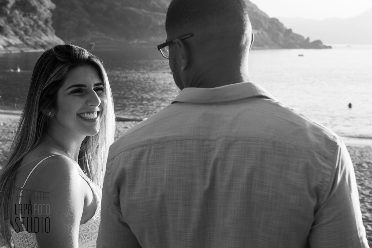 Foto em preto e branco da noiva sorrindo para o noivo no pré wedding na praia vermelha
