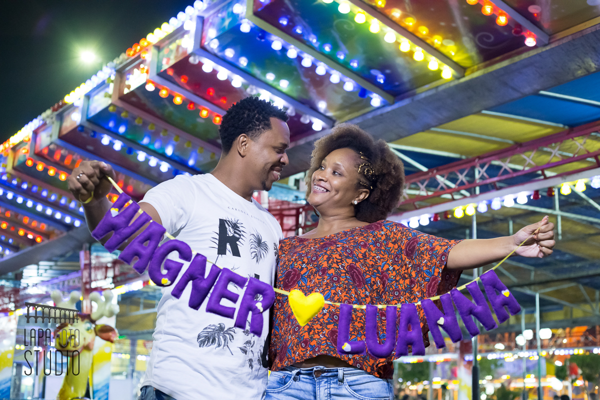 Noivos seguram varal com nome deles no dia do pré wedding no parque de diversões