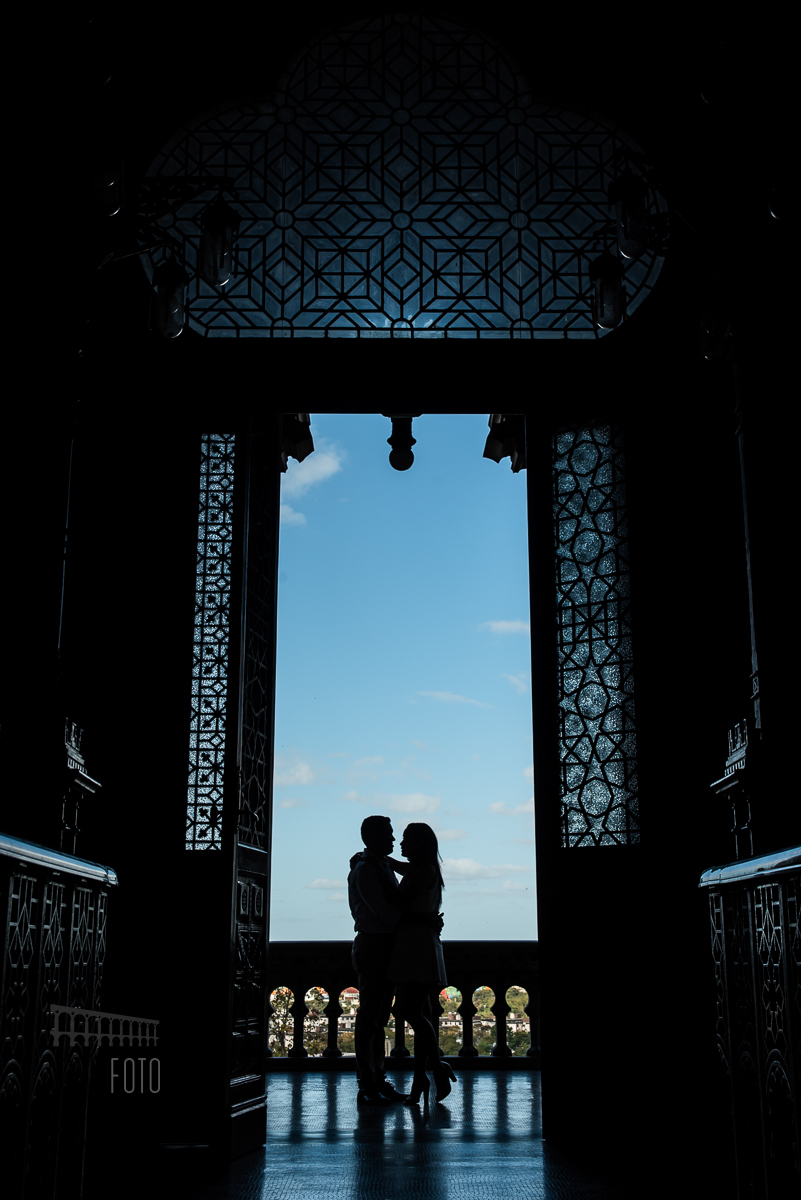 Foto em contraluz dos noivos na porta da Fiocruz no dia do ensaio pré casamento