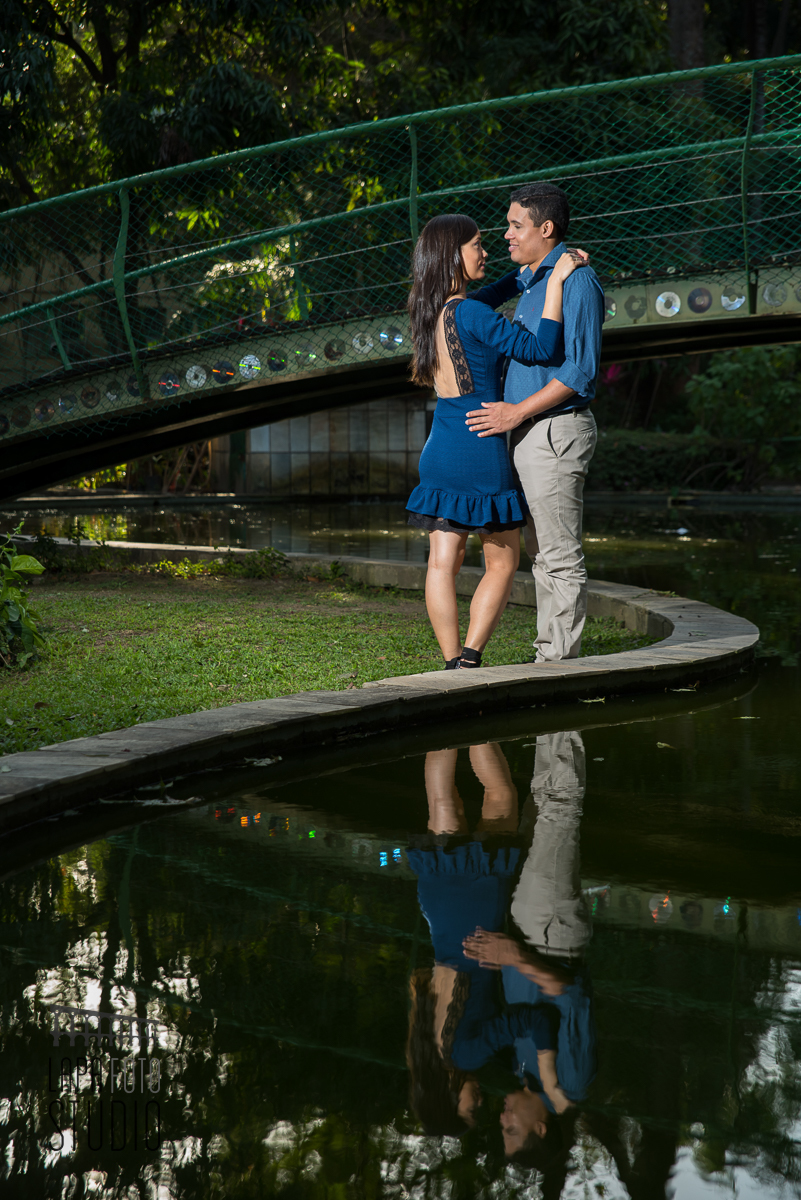 Noivos na beirada do lago com reflexo na água na Fiocruz