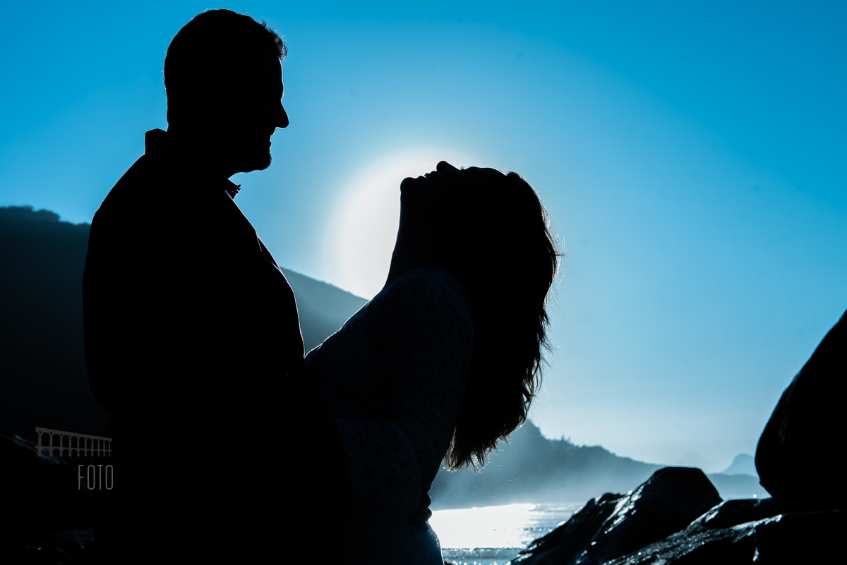 Noivos em contraluz com céu azul no dia do pré wedding na praia