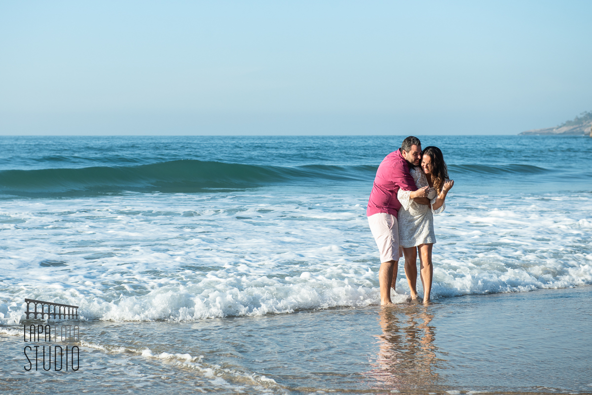 Noivos na beirada da água se divertindo no pré wedding na Prainha