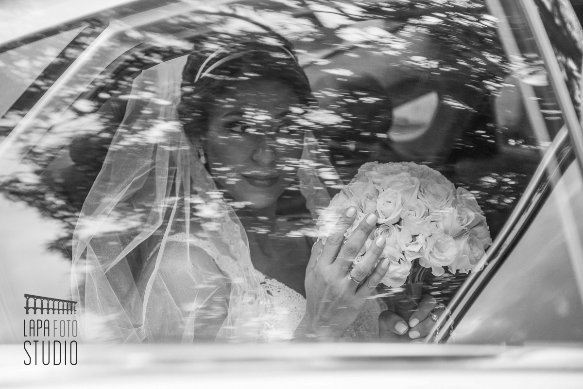 Foto em preto e branco da noiva chegando de carro para cerimônia de casamento