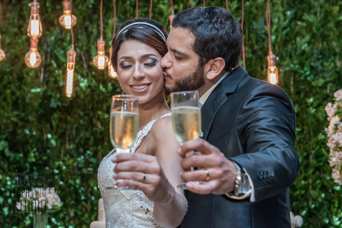 Noivo beija o rosto da noiva durante brinde de casamento