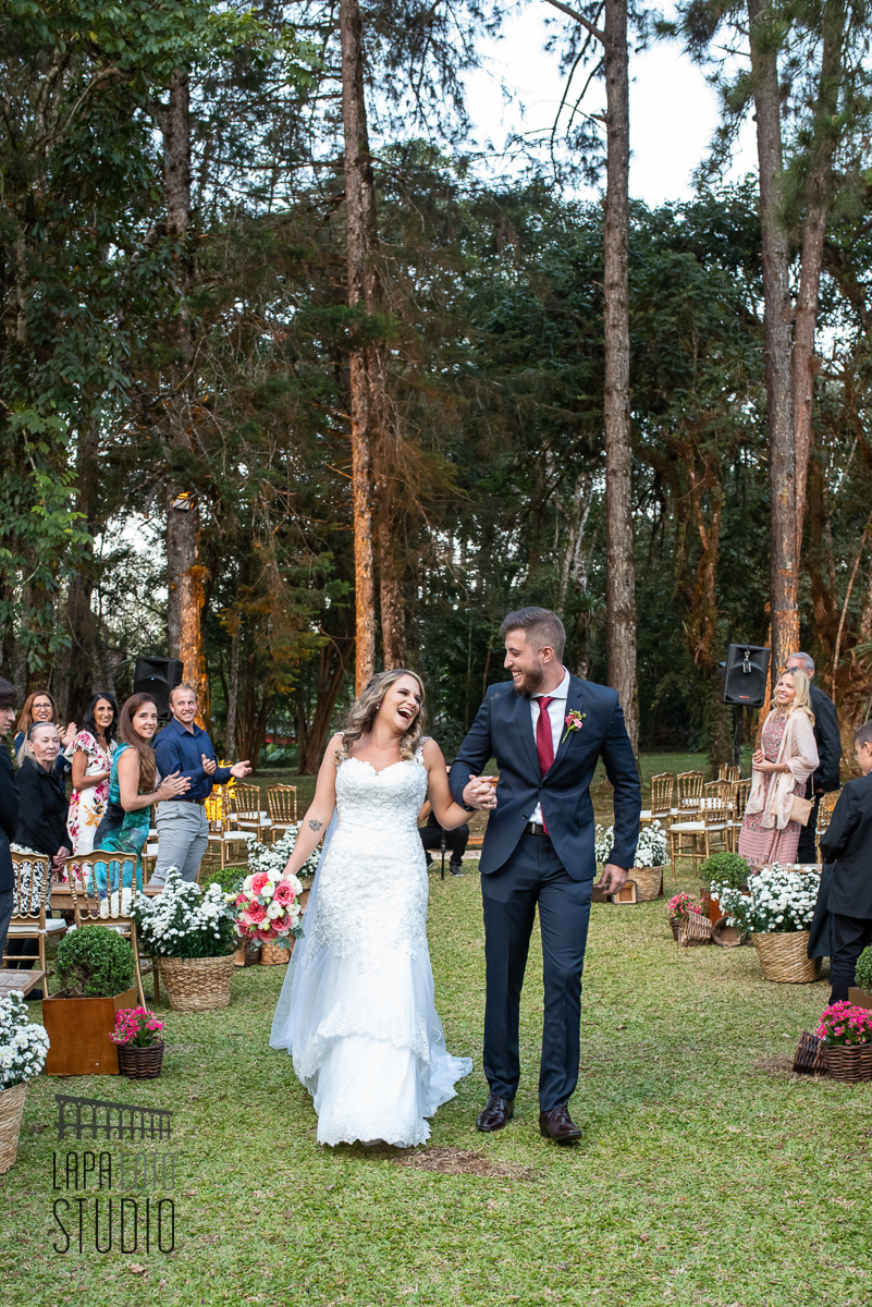 Noivos sorridentes saindo da cerimônia de casamento em Visconde de Maua