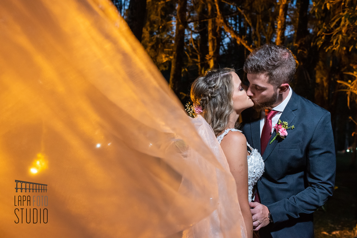 Noivos se beijam com véu aparecendo em Visconde de Mauá