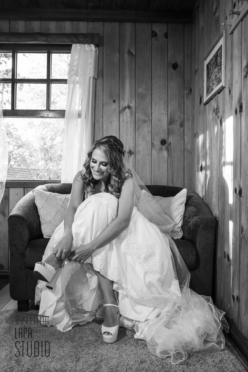 Foto em preto e branco da noiva colocando seus sapatos