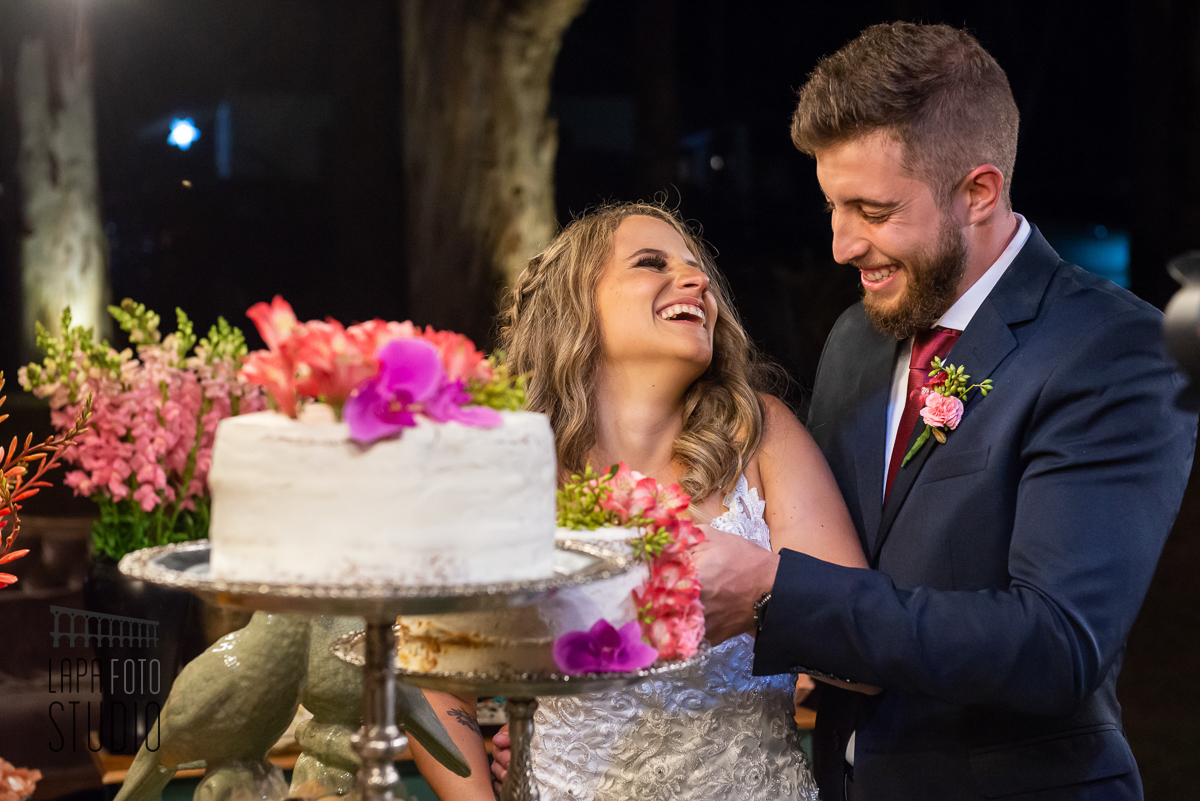 Noivos sorriem no corte do bolo na festa de casamento em Visconde de Mauá