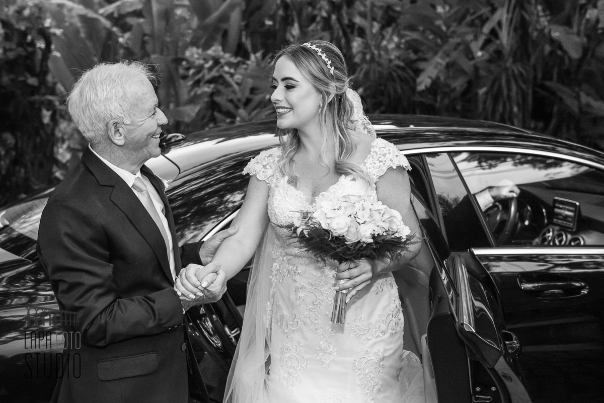 Foto em preto e branco do pai tirando a noiva do carro para cerimônia de casamento no Espaço Paradisus