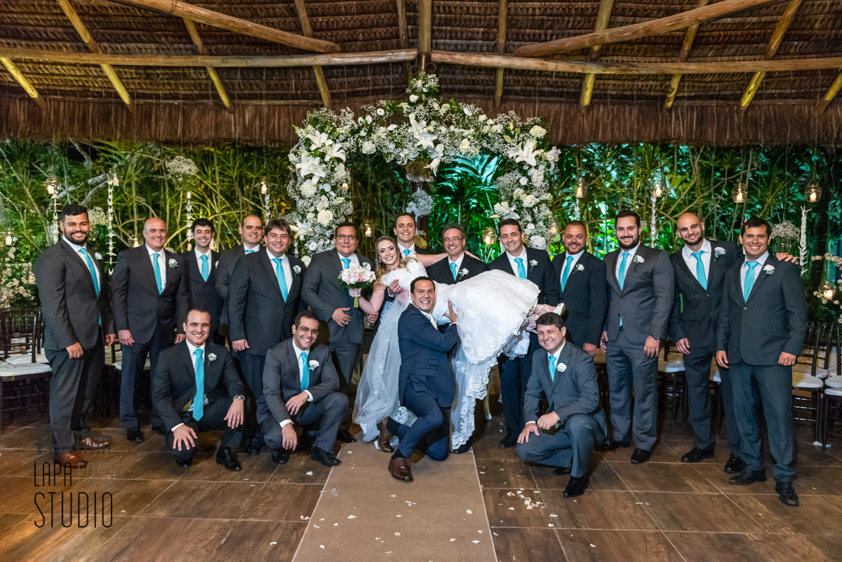 Padrinhos pegam a noiva no colo com noivo logo abaixo durante sessão de fotos no espaço Paradisus