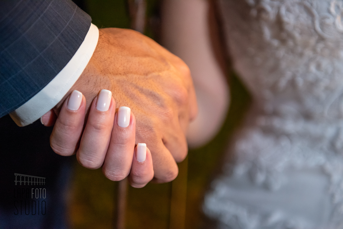 Close das mãos dos noivos trocando carinhos no ensaio pós cerimônia de casamento