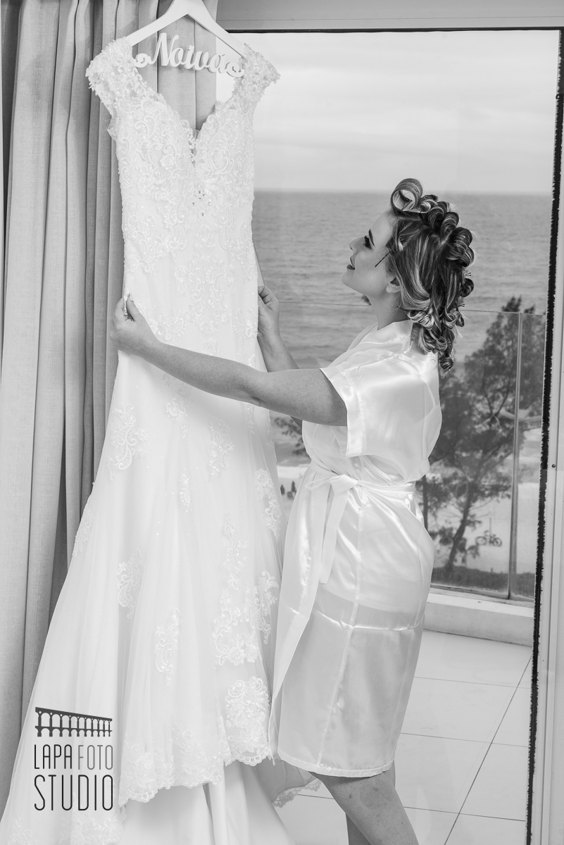 Foto em preto e branco da noiva admirando seu vestido no hotel c design barra