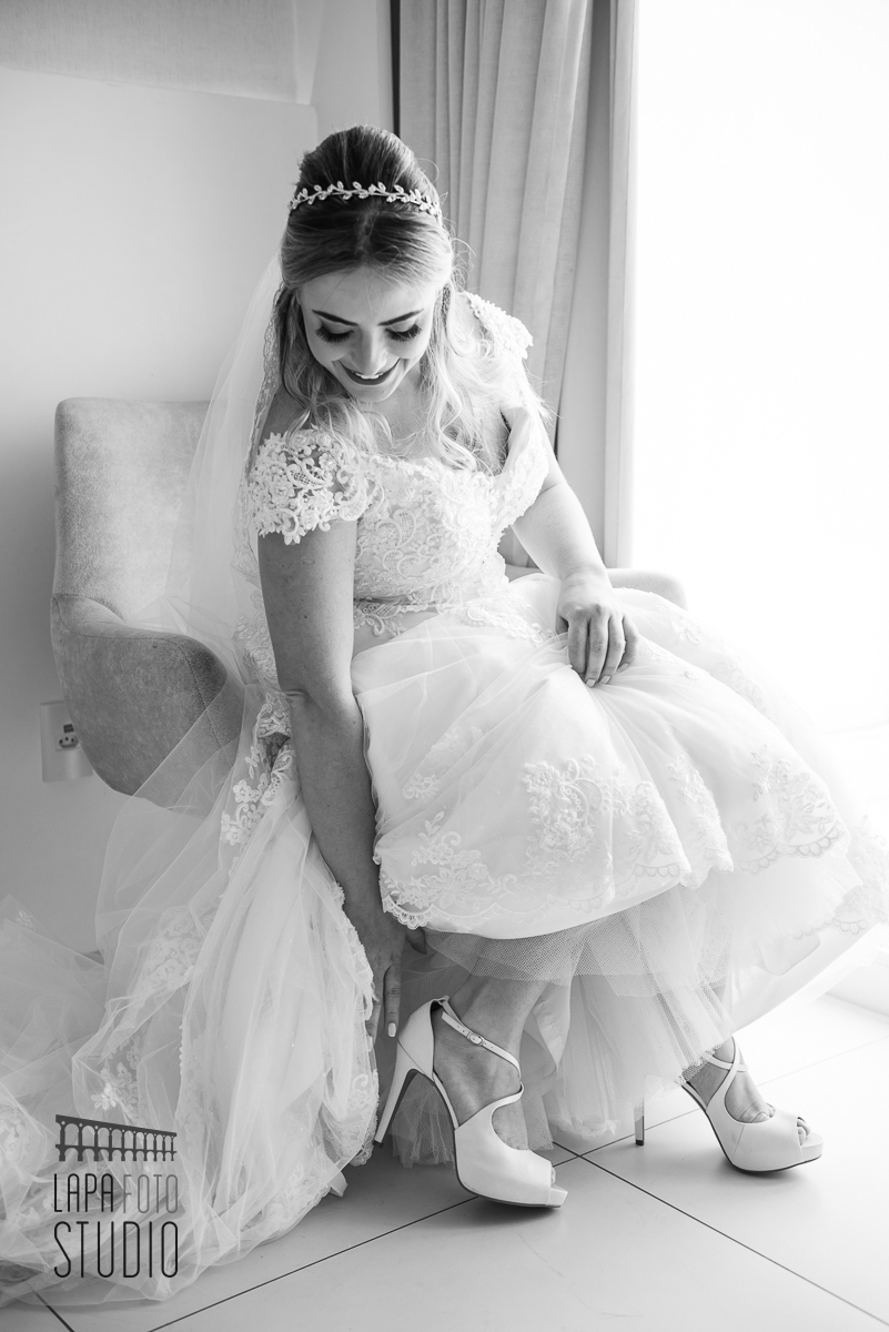 Foto em preto e branco da noiva calçando seus sapatos no hotel c design barra