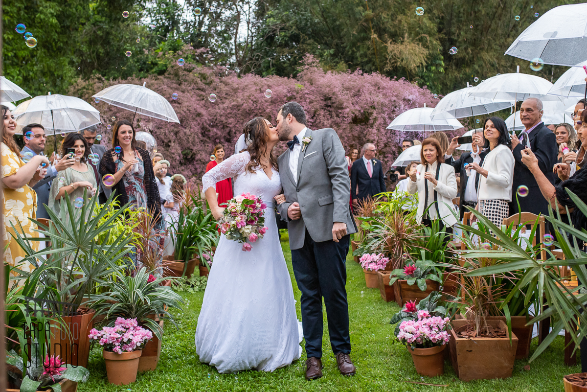 Noivos se beijam durante a saída da cerimônia de casamento no Sítio Meio do Mato 