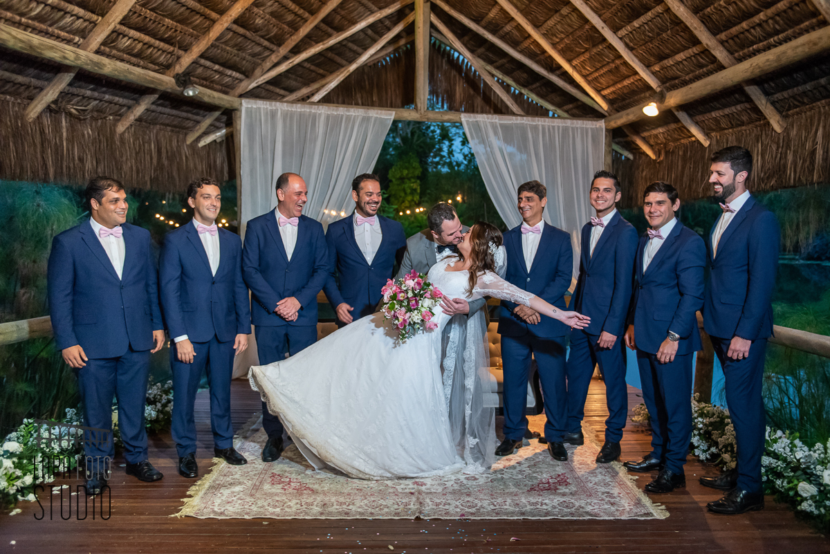 Noivos se beijam com padrinhos observando na sessão de fotos no casamento no Meio do Mato Eventos