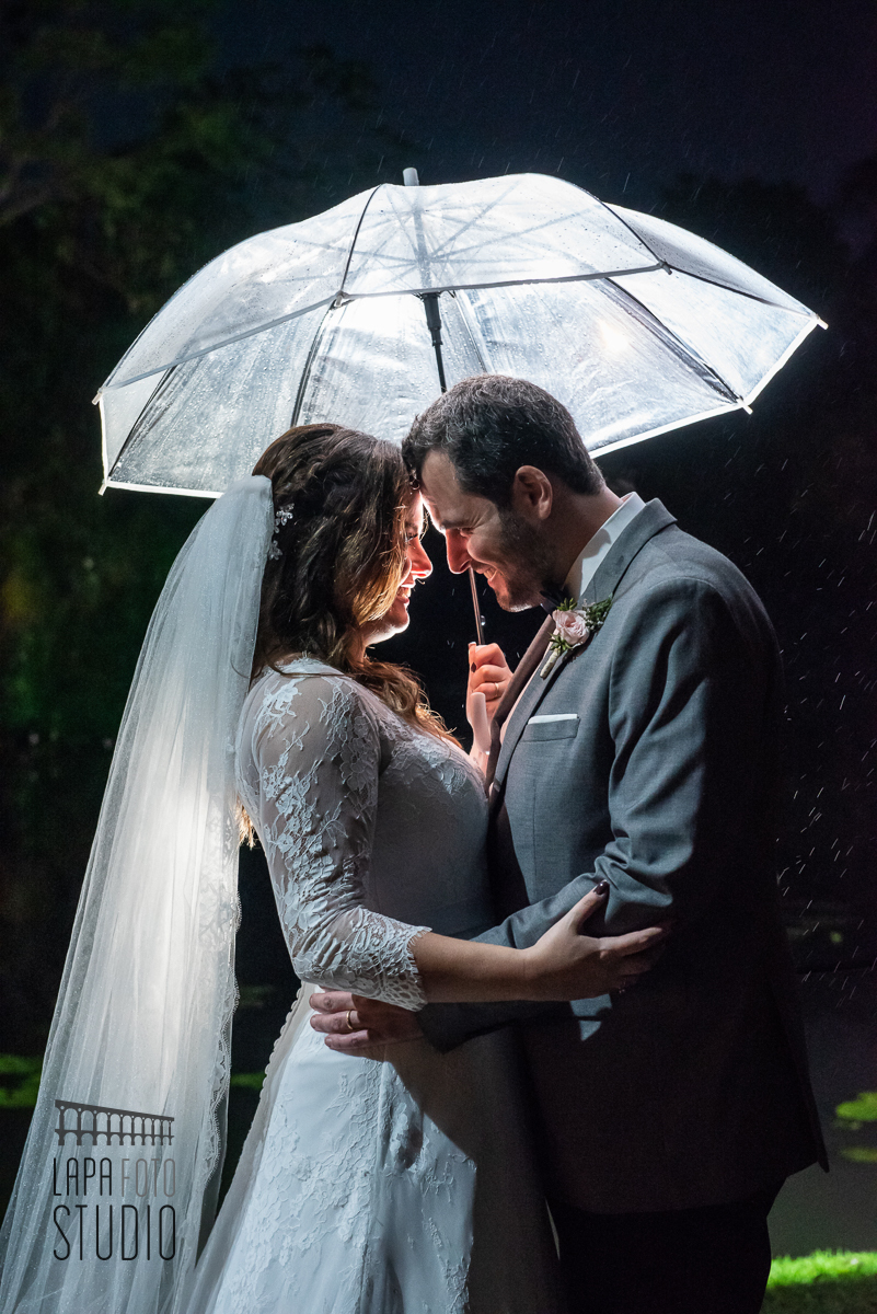 Noivos com guarda chuva em contra luz após cerimônia de casamento no Meio do Mato Eventos