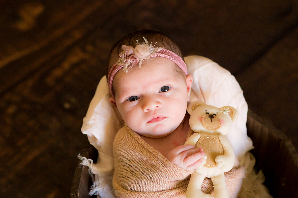 Ensaio newborn em Pará de Minas com bebê acordado. Pose no prop, baldinho com ursinho.