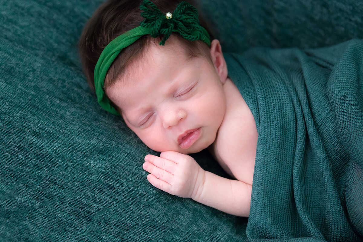 Fotografia de newborn em Pará de Minas. Pose no puff na manta verde.