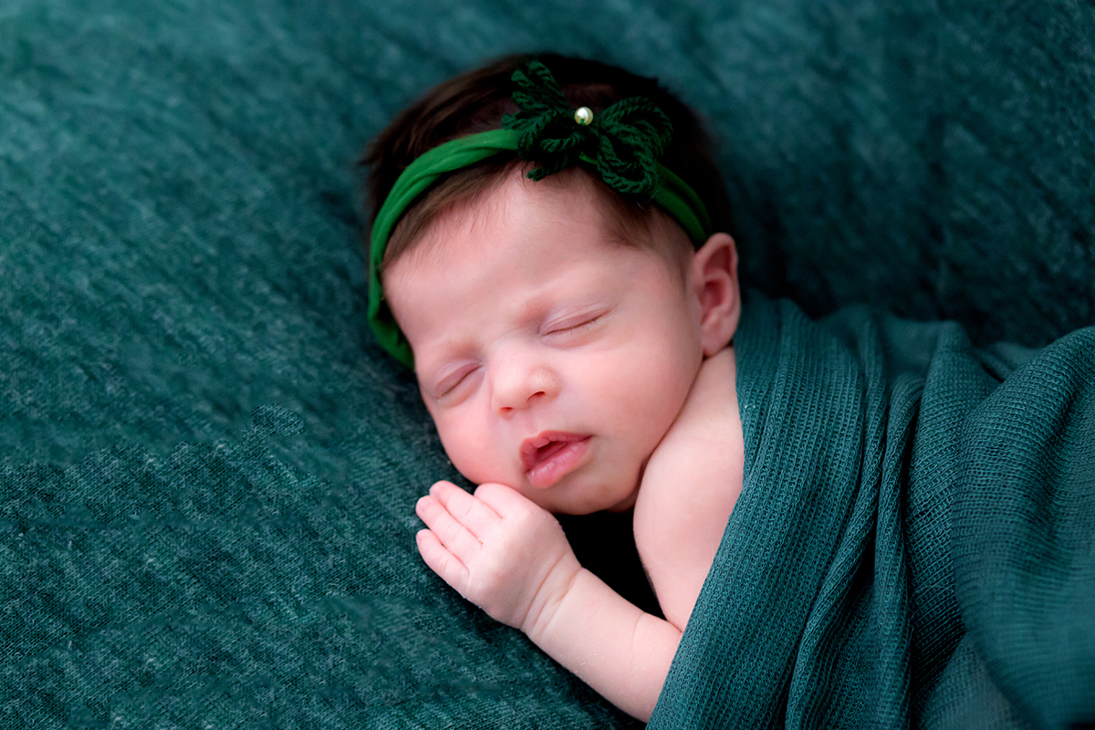 Ensaio de newborn em Pará de Minas. Pose no puff com manta e wrap verde.