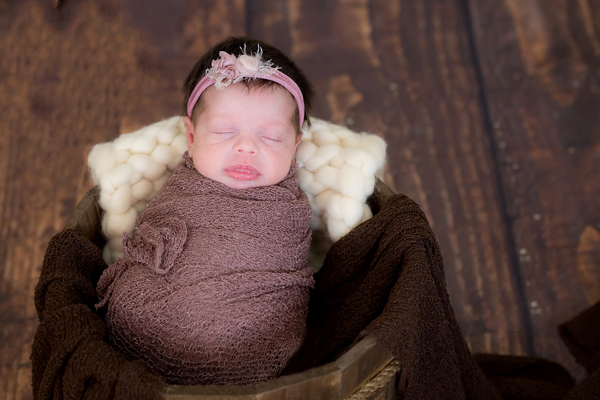 Ensaio de Newborn em Pará de Minas. Belê enrolado no wrap, pose no prop e piso de madeira.