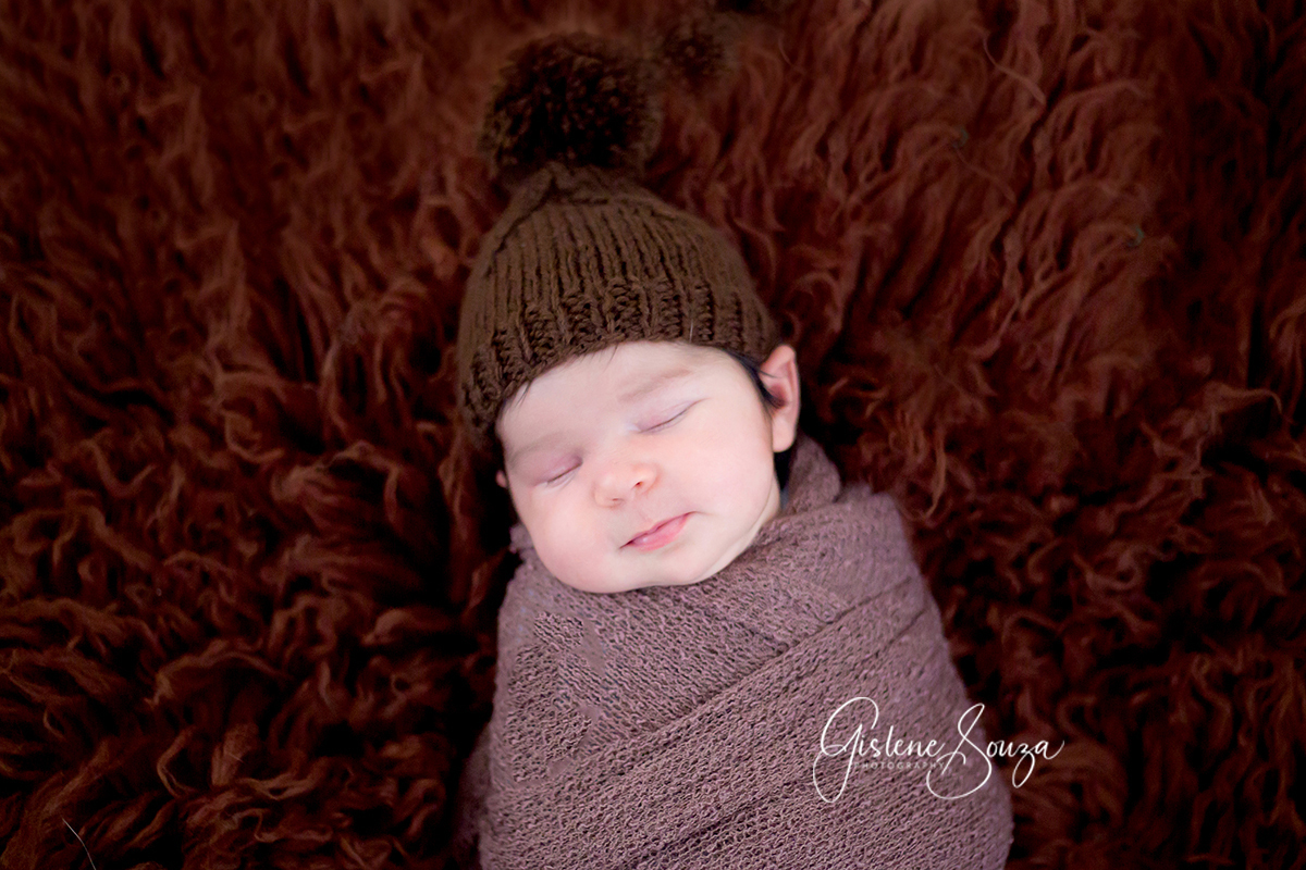 Ensaio de newborn em Belo Horizonte. Bebê menina pose no pelo sobre o puff.