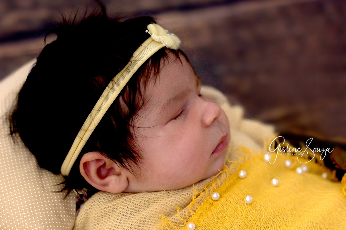 Fotografia de newborn em Belo Horizonte. Pose no prop em tons de amarelo com fundo em madeira.