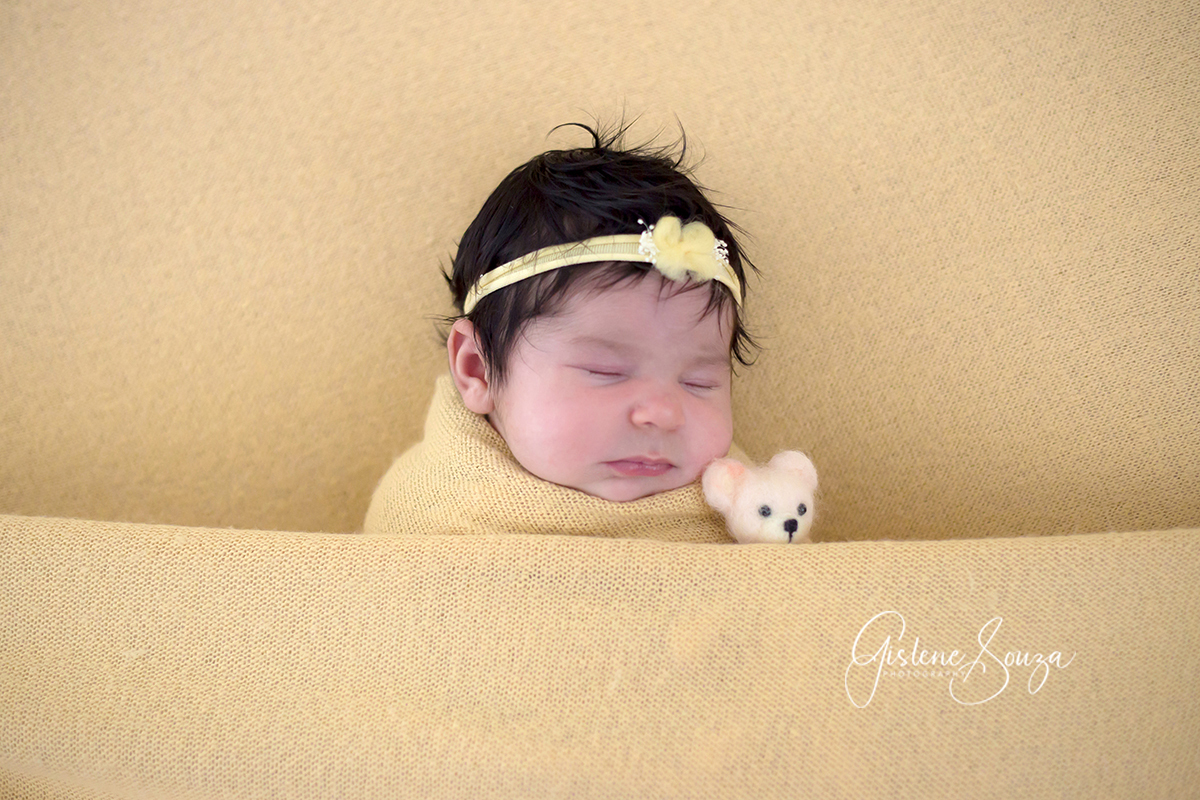 Ensaio newborn de barriga para cima no puff. Bebê menina. Composição monocromática em amarelo. Realizado em Belo Horizonte.