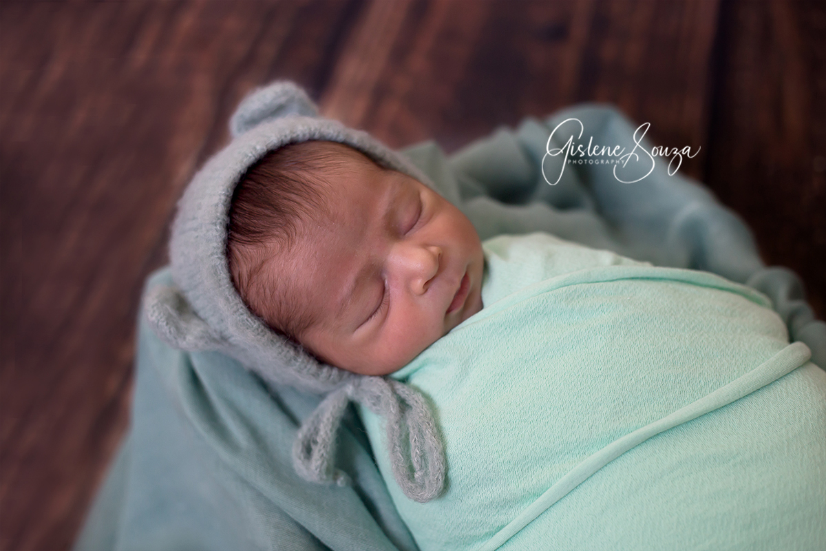 Fotografia de newborn em Belo Horizonte, no pop com fundo de madeira, usando tons de verde.