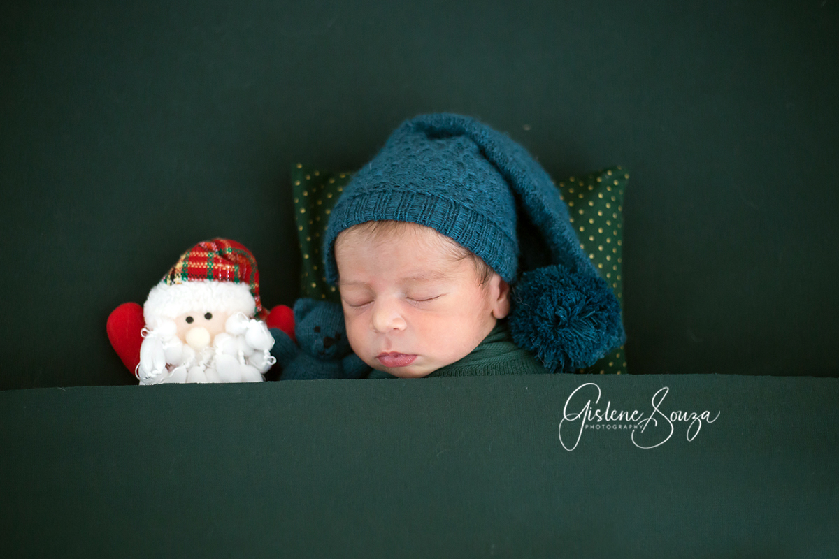 Ensaio newborn de natal em Belo Horizonte. Pose no puff de barriguinha para cima com papai noel.