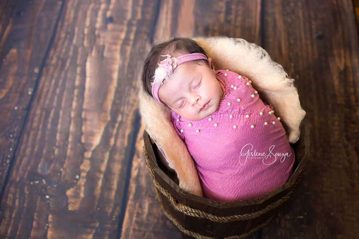Fotografia de Newborn Belo Horizonte. Bebê posicionado no prop com fundo de madeira. Newborn de menina em rosa.