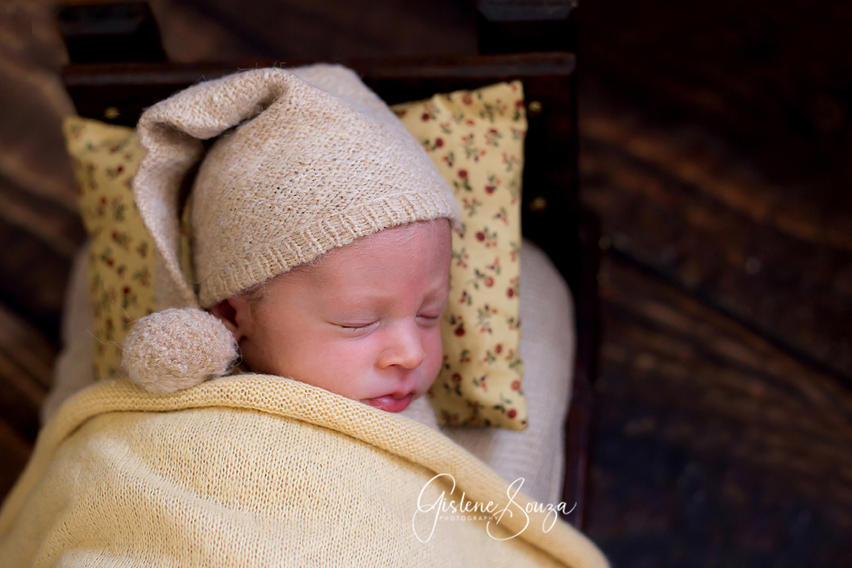 Ensaio de newborn em Belo Horizonte, pode na caminha. Piso de madeira. Newborn no prop com touca soneca.