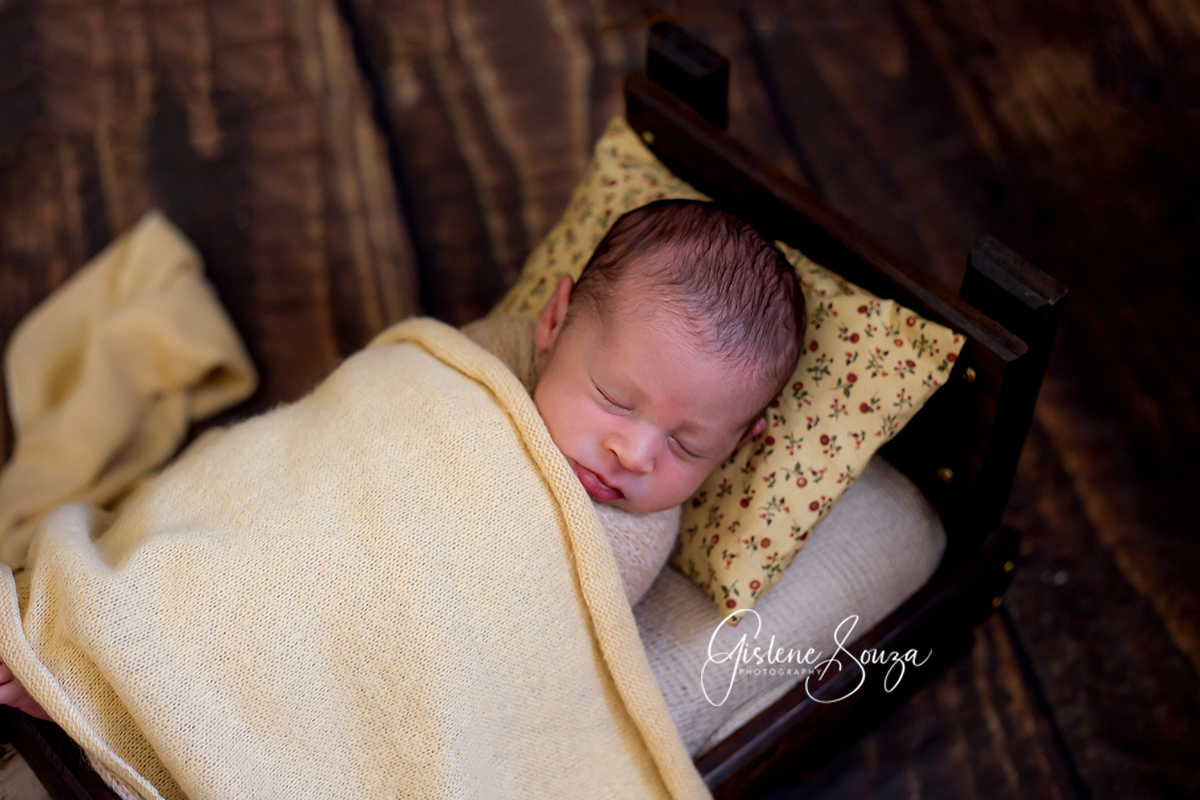 Ensaio de newborn. Fotografia realizada em Belo Horizonte. Newborn pose no prop caminha com wrap amarelo.